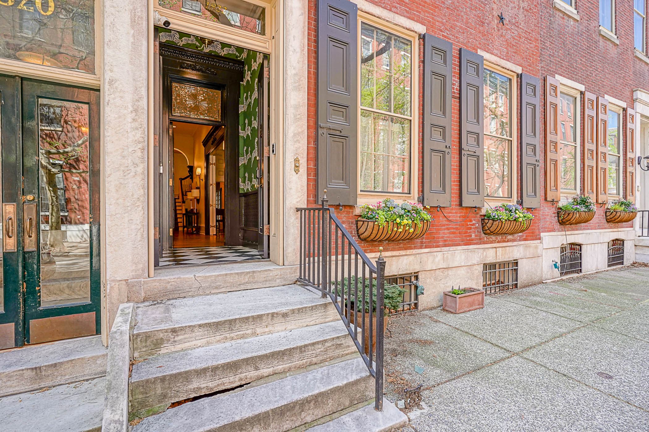 Red-brick Victorian facade of The Rittenhouse Residence with flower boxes and the front door open